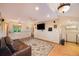 Bright living room with hardwood floors, area rug, leather couch, ceiling fans, and a large screen TV at 10592 Raven Run, Littleton, CO 80125