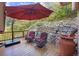 Wood patio featuring an umbrella and two cushioned chairs, with a stone wall backdrop at 10592 Raven Run, Littleton, CO 80125