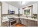 Modern kitchen with stainless steel appliances, white cabinets, and a bright window overlooking the backyard at 245 Main St, Broomfield, CO 80020