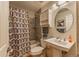 Well-lit bathroom featuring tiled shower, patterned shower curtain, pedestal sink, mirrored medicine cabinet and linen storage at 7945 York St # 2, Denver, CO 80229