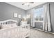 Cozy bedroom with a white crib, neutral walls, and a large window with elegant curtains at 25148 E Lake Pl, Aurora, CO 80016