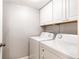 This laundry room has a white washer, dryer, and upper cabinets for storage at 14100 E Temple Dr # W01, Aurora, CO 80015