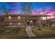 Beautiful home at dusk featuring a well-lit walkway, manicured lawn, brick and stucco exterior at 1095 Lake Woodmoor Dr, Monument, CO 80132