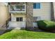 Exterior corner of a condo featuring a balcony with stone accents and manicured greenery at 8555 Fairmount Dr # G103, Denver, CO 80247
