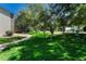 Green space with mature trees providing shade, a sidewalk, and pet waste disposal bags at 8555 Fairmount Dr # G103, Denver, CO 80247