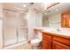 Bathroom featuring a glass-enclosed shower, a wooden vanity, and neutral-toned wallpaper at 7500 E Dartmouth Ave # 16, Denver, CO 80231