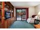 Cozy living room featuring built-in wooden shelves, a comfortable chair, and a sliding door to the backyard at 7500 E Dartmouth Ave # 16, Denver, CO 80231