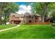 Expansive lush backyard of red brick home featuring mature trees, a privacy fence and manicured lawn at 290 Dexter St, Denver, CO 80220