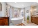 Bright bathroom with a freestanding tub, neutral tile, and plentiful natural light from three windows at 290 Dexter St, Denver, CO 80220