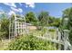 A charming garden features a white arbor, colorful plants, and a wooden fence at 2440 Saulsbury St, Lakewood, CO 80214