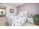 Bright bedroom showcasing a comfortable bed, nightstand, and calming lilac accent wall at 8465 Pebble Creek Way # 102, Highlands Ranch, CO 80126