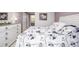 Bright bedroom featuring bed, dresser, and an open view to an en suite bath at 8465 Pebble Creek Way # 102, Highlands Ranch, CO 80126