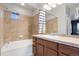 Well-lit bathroom with bath and shower, tiled walls, and wooden vanity at 13000 W Grant Cir # C, Thornton, CO 80241