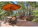 Relax on this spacious deck with an orange umbrella, outdoor seating, and views of the surrounding trees at 929 Coneflower Dr, Golden, CO 80401