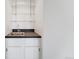 Wet bar featuring a sleek counter, stainless steel sink, white cabinets, and modern glass shelving at 7865 E Mississippi Ave # 1502, Denver, CO 80247