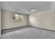 A gray carpeted bedroom with a window and neutral-colored walls under a spotlight at 9099 W Harvard Pl, Lakewood, CO 80227