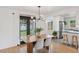 The stylish dining area features a modern chandelier, black-framed doors, and views of the updated kitchen at 3440 N Harrison St, Denver, CO 80205