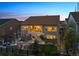 Two-story home with outdoor patio, pergola, firepit and manicured backyard at dusk at 8621 S De Gaulle Ct, Aurora, CO 80016