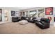 Spacious living room with a large sectional sofa, plush carpet, and bright natural light from expansive windows at 8621 S De Gaulle Ct, Aurora, CO 80016
