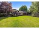 A spacious backyard offering a lush green lawn, mature trees, and a wooden deck with access to the home at 9951 Winona St, Westminster, CO 80031