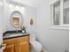 Half bathroom featuring wood vanity, black granite countertop, oval mirror, and updated lighting at 9951 Winona St, Westminster, CO 80031