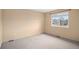 This is an empty bedroom with neutral walls and carpet and a well-lit window with neighborhood views at 6911 Chestnut Ct, Parker, CO 80134