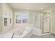 Sunlit bathroom with a soaking tub, a separate glass shower, and a large window at 6911 Chestnut Ct, Parker, CO 80134