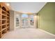 Sunlit home office with custom wood shelving, arched windows, and neutral carpet at 6911 Chestnut Ct, Parker, CO 80134