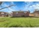 Large back yard with grass, brick house, and mature trees on a sunny day at 3022 Blackhawk St, Aurora, CO 80011