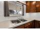 Double sink in kitchen with tile backsplash, white countertops and wooden cabinets at 3022 Blackhawk St, Aurora, CO 80011