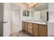 Bathroom featuring a double sink vanity with wood cabinets and a large mirror and door to bedroom at 18807 E 51St Pl, Denver, CO 80249