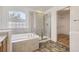 Bathroom featuring a tiled tub, glass-enclosed shower, and a doorway to the walk-in closet at 18807 E 51St Pl, Denver, CO 80249