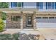 Inviting front porch with stone pillars leading to a navy blue front door with glass pane at 18807 E 51St Pl, Denver, CO 80249