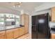 Open kitchen area with wood cabinetry, black appliances, and an arched doorway view into the living room at 18807 E 51St Pl, Denver, CO 80249