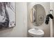 Well-appointed powder room with a pedestal sink, oval mirror, and modern wall art at 4853 Cattle Cross Ln, Castle Rock, CO 80104