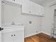 Functional laundry room with white cabinetry, a utility sink, and hardwood flooring for easy maintenance at 9734 Tall Grass Cir, Lone Tree, CO 80124