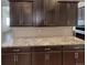 Close-up of the kitchen with granite countertops, dark wood cabinets, and a tile backsplash at 1220 W 170Th Ave, Broomfield, CO 80023