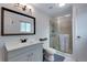 Bright bathroom features a shower, a dark framed mirror and gray cabinets at 147 Wallace St, Northglenn, CO 80234