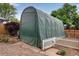 Backyard featuring a large, green, industrial looking protective cover over a garden or play area enclosed by a white picket fence at 147 Wallace St, Northglenn, CO 80234