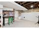 Basement space features brick accent wall, concrete floor, exposed ceiling beams, and green stool at 4403 Alcott St, Denver, CO 80211