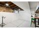 Unfinished basement area showcasing concrete floors, exposed ceiling beams, and brick with a green stool at 4403 Alcott St, Denver, CO 80211