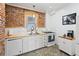 Well-lit kitchen featuring painted brick, white cabinetry, and stainless steel gas range at 4403 Alcott St, Denver, CO 80211