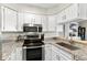 Well-lit kitchen boasts stainless steel appliances, granite countertops, and white cabinets for a clean, modern feel at 10715 Foxwood Ct, Parker, CO 80138