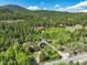 Expansive aerial view of a property nestled amidst lush green forests and rolling hills, highlighting its serene and private location at 63 Sillasen Ln, Golden, CO 80403