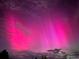 Vibrant pink Aurora Borealis illuminates the night sky, creating a mesmerizing and ethereal display at 63 Sillasen Ln, Golden, CO 80403