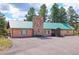 Brick exterior with green roof and a large stone chimney, complemented by well-maintained landscaping at 63 Sillasen Ln, Golden, CO 80403