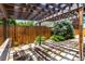 This backyard is covered with stone pavers and has a pergola, wooden fence, and mature trees at 1015 S Fulton Ave, Fort Lupton, CO 80621