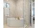 Bright bathroom featuring an oval soaking tub, glass enclosure, and marble-tiled walls at 2113 Fountain Cir, Erie, CO 80516