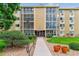 Inviting exterior of a multi-story condo building with lush landscaping and walkway at 13626 E Bates Ave # 110, Aurora, CO 80014