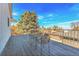 Covered wood deck featuring metal patio furniture and views of mature trees at 13577 W Alaska Dr, Lakewood, CO 80228